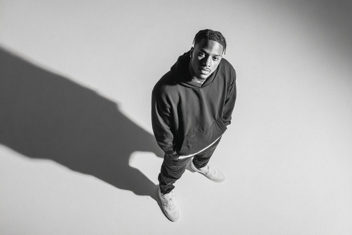 A [subject] photographed from a 35-degree overhead angle, standing alone in an off-white studio void, with a confident p