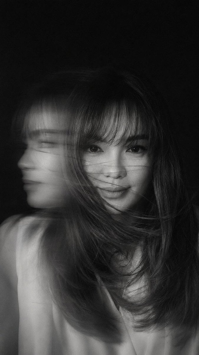 A hyper-realistic, cinematic black-and-white portrait of a woman caught in mid-motion, her face partially obscured by sw