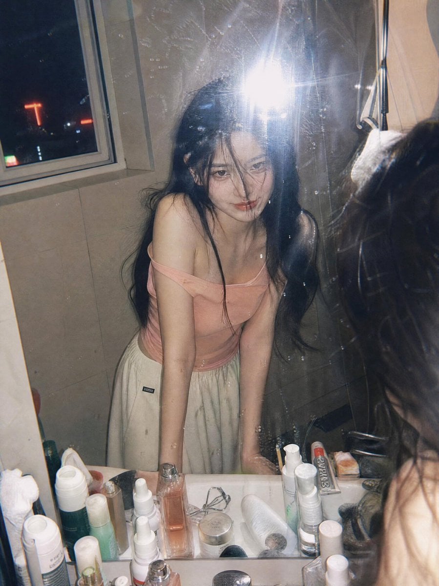 Ultra-realistic candid film photography portrait of a young woman leaning over a bathroom sink and looking into a mirror