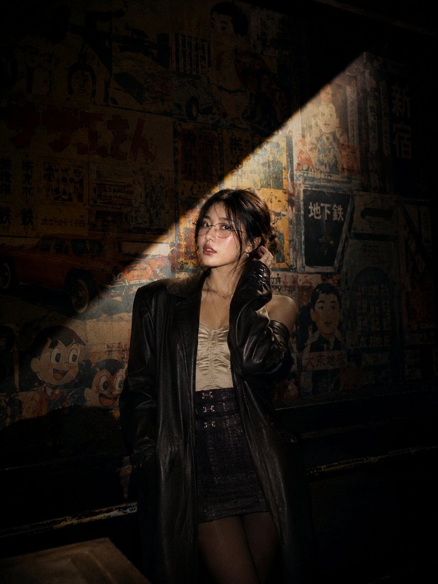 Cinematic nighttime portrait of a stylish young Asian woman standing on an escalator inside a modern Japanese-themed ent