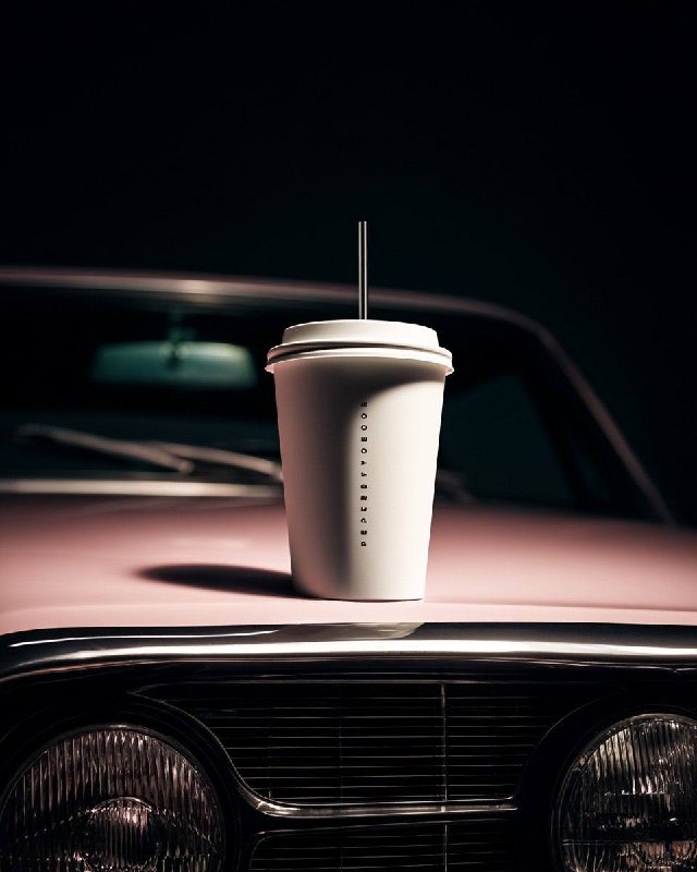 minimal cinematic product shot, a white takeaway cup with lid and straw placed o…